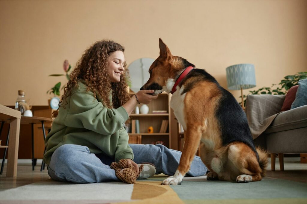 happy girl giving treats to pet dog in home together 1.jpg